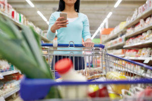 woman with smartphone buying food at supermarket