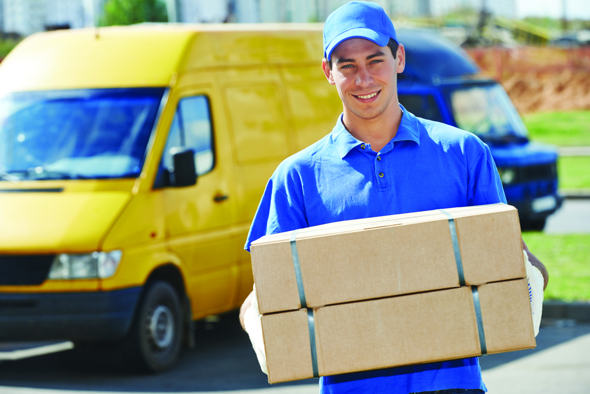 Smiling young male postal delivery courier man in front of cargo van delivering package